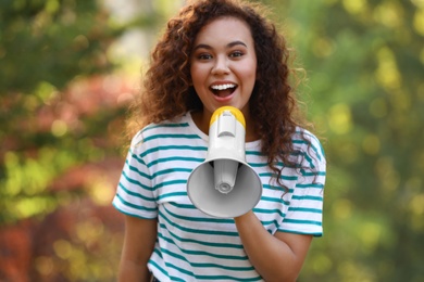 Happy African-American woman with megaphone outdoors. Meeting leader