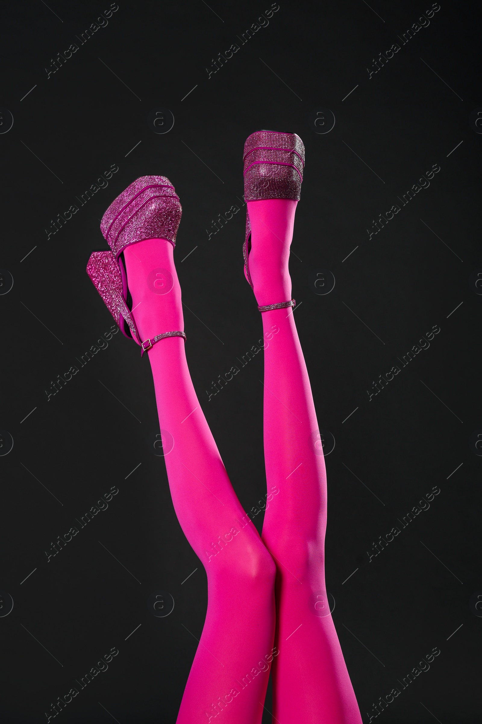 Photo of Woman wearing pink tights and high heeled shoes with platform and square toes on black background, closeup