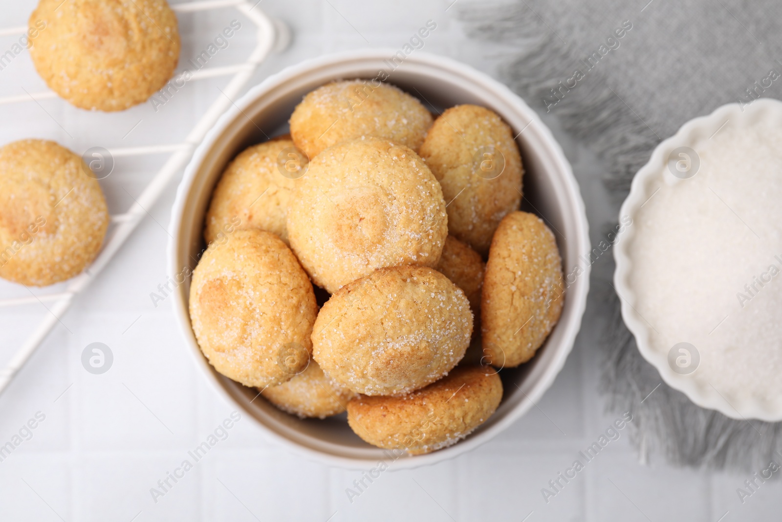 Photo of Tasty sugar cookies in bowl on white tiled table, top view