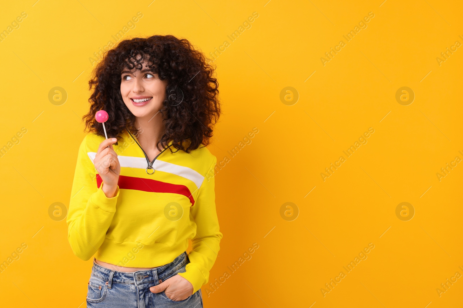 Photo of Beautiful woman with lollipop on yellow background, space for text