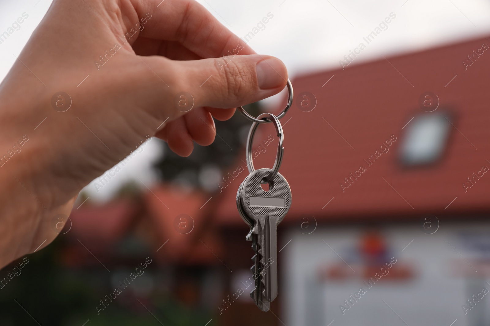 Photo of Real estate agent holding keys to new house outdoors, closeup