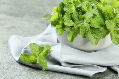 Photo of Bowl with fresh green mint leaves on grey table, closeup
