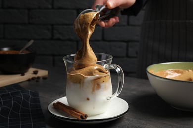 Photo of Woman making dalgona coffee at grey table, closeup