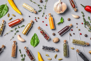 Photo of Glass bottles with different spices on gray background