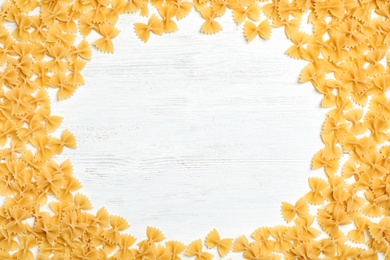 Photo of Frame made of raw pasta on wooden background