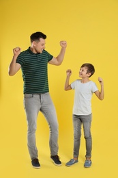 Portrait of emotional dad and his son on color background