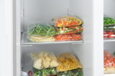 Plastic bags with different frozen vegetables in refrigerator