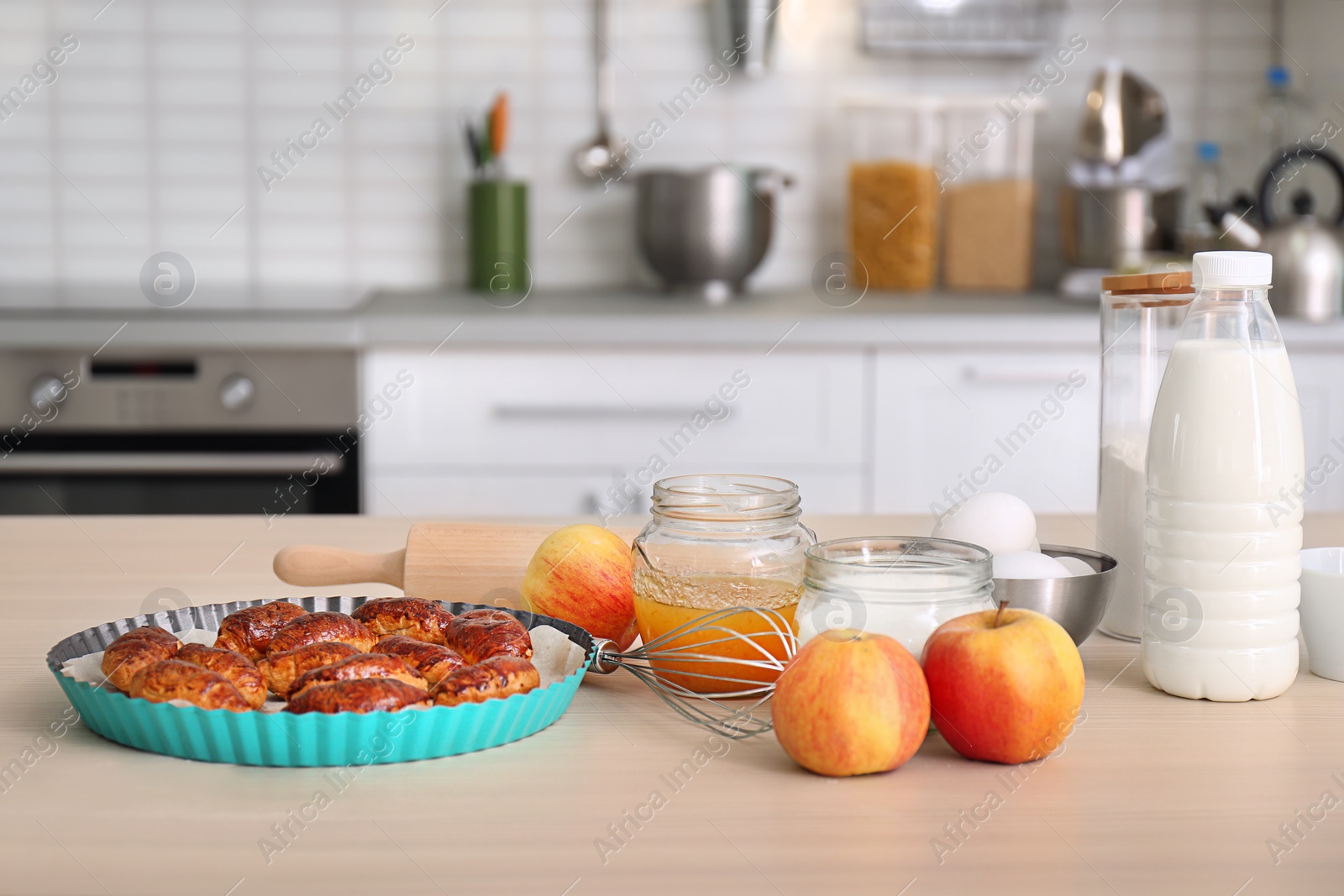 Photo of Baking dish with delicious croissants and products on kitchen table