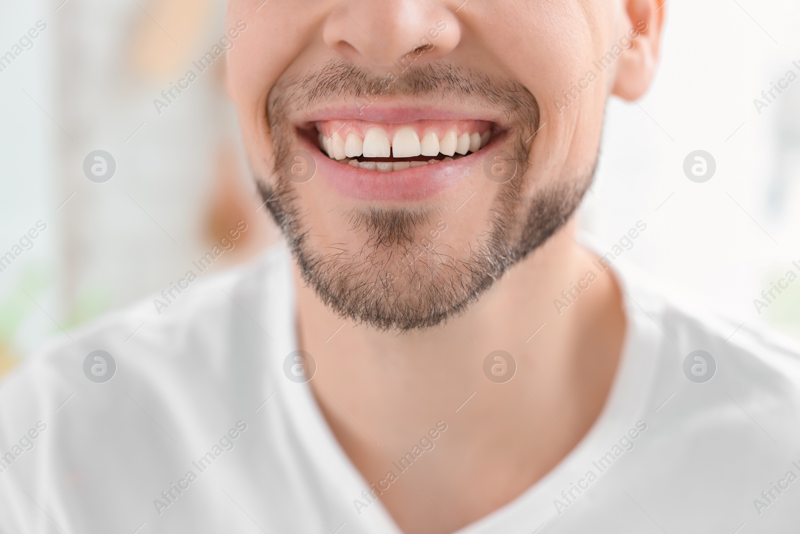 Photo of Young man with beautiful smile indoors. Teeth whitening