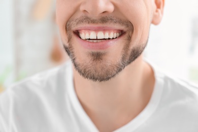 Photo of Young man with beautiful smile indoors. Teeth whitening