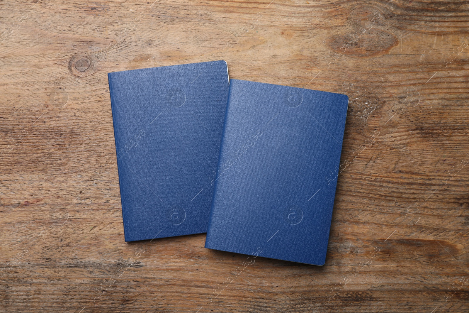 Photo of Blank blue passports on wooden table, flat lay