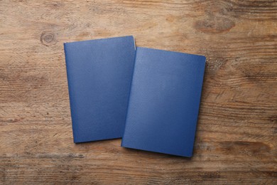 Photo of Blank blue passports on wooden table, flat lay