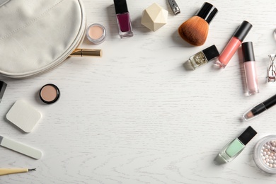 Flat lay composition with cosmetics, bottles of nail polish and space for text on white wooden background