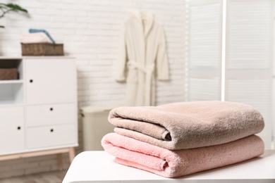 Photo of Clean folded towels on table in bathroom. Space for text