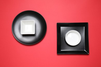 Set of ceramic dishware on red background, flat lay