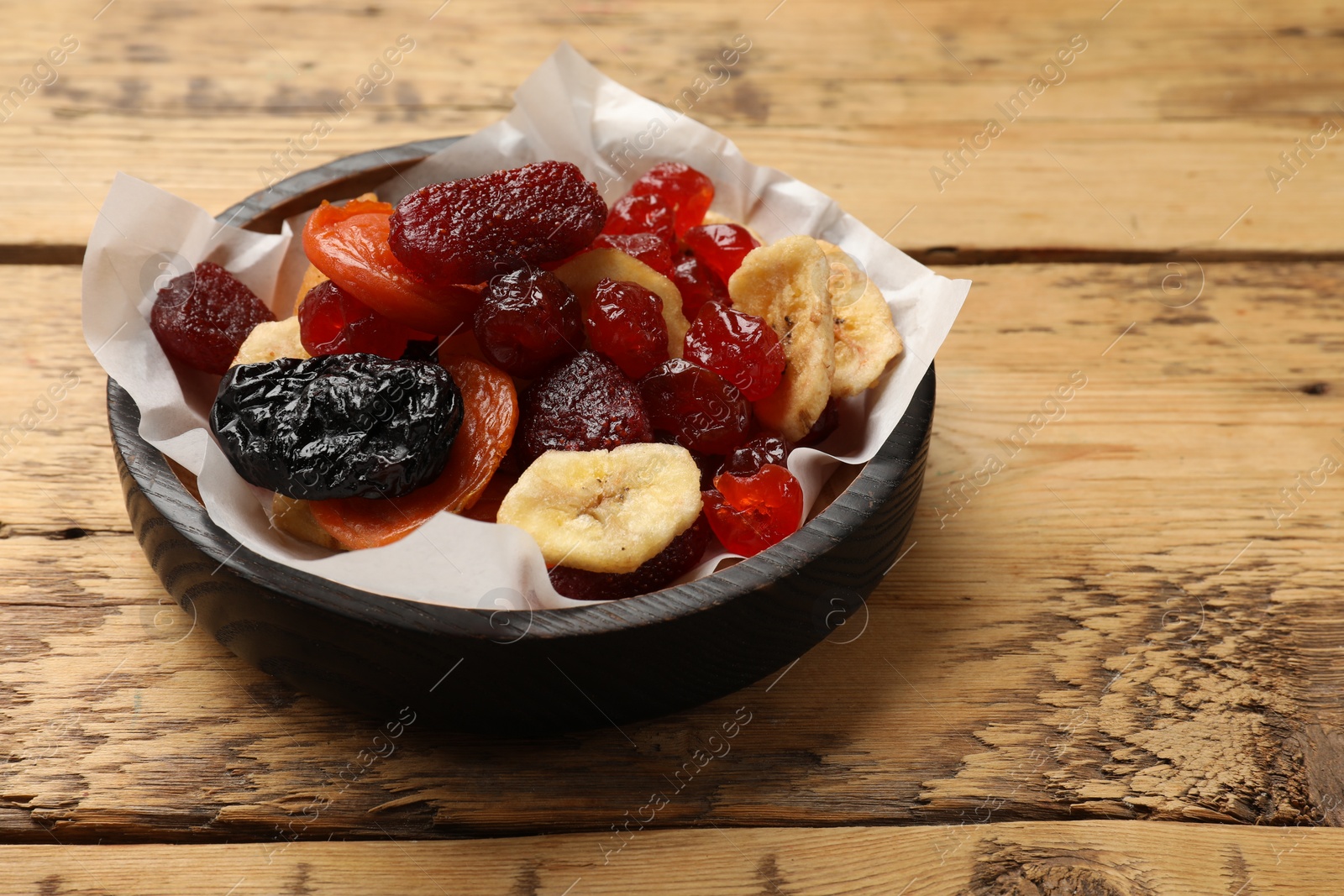 Photo of Mix of delicious dried fruits on wooden table. Space for text