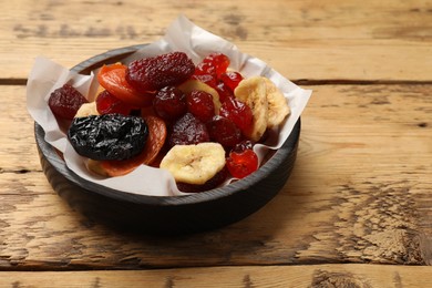 Photo of Mix of delicious dried fruits on wooden table. Space for text