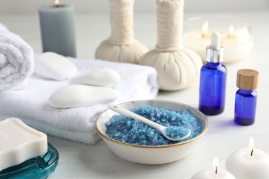 Photo of Spa composition. Cosmetic products, soap, towels, sea salt and burning candles on light table