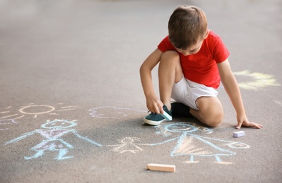 Little child drawing family with chalk on asphalt