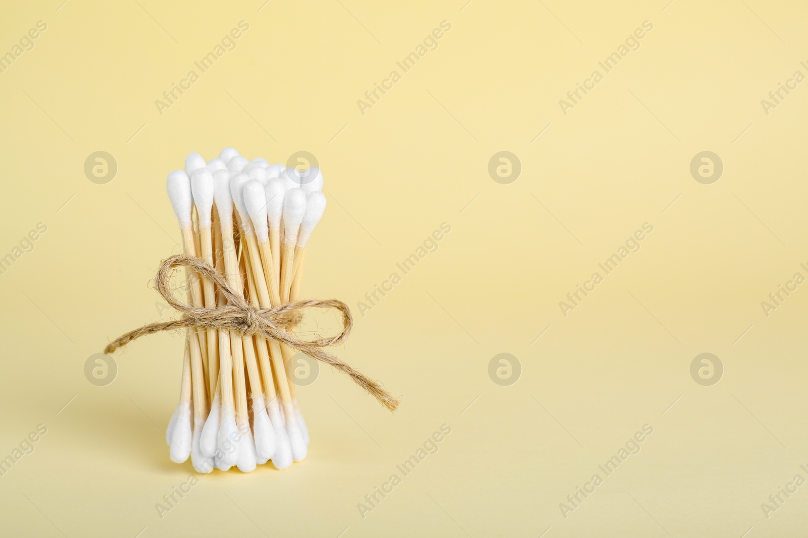 Photo of Bunch of wooden cotton buds on beige background. Space for text