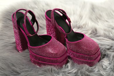 Photo of New pink high heeled shoes with platform and square toes on grey fur, closeup