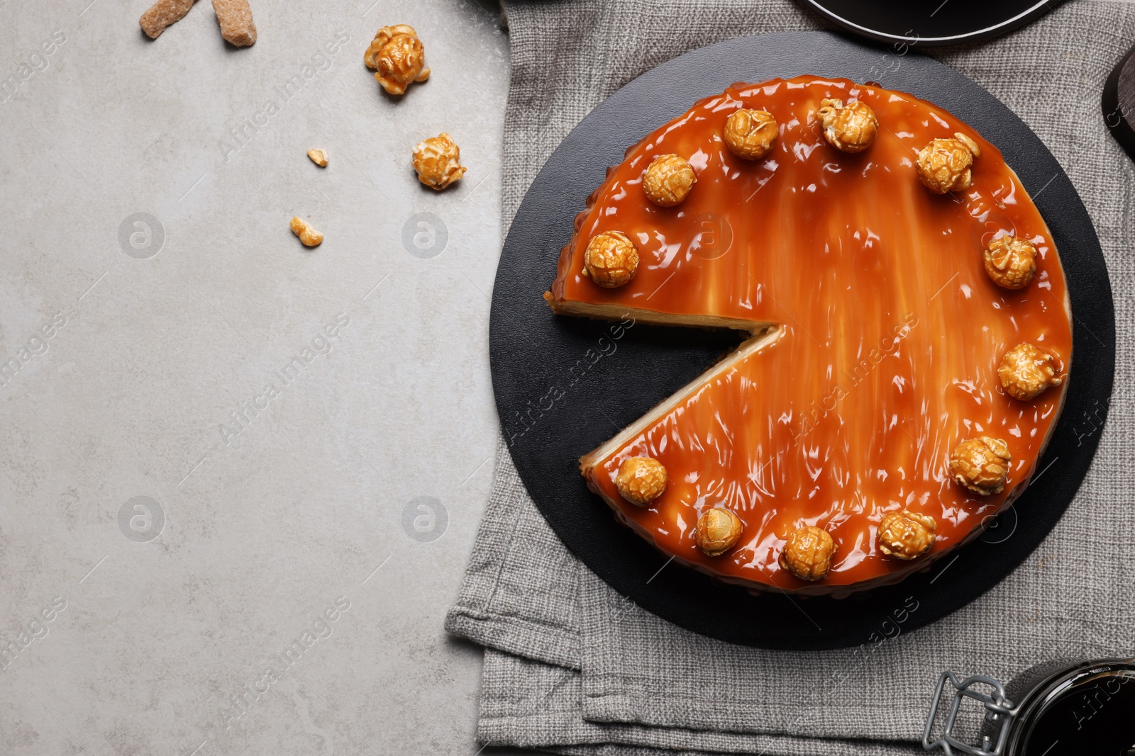 Photo of Sliced delicious cheesecake with caramel and popcorn served on light grey table, flat lay. Space for text