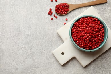 Photo of Aromatic spice. Red pepper in bowl and spoon on light textured table, top view. Space for text