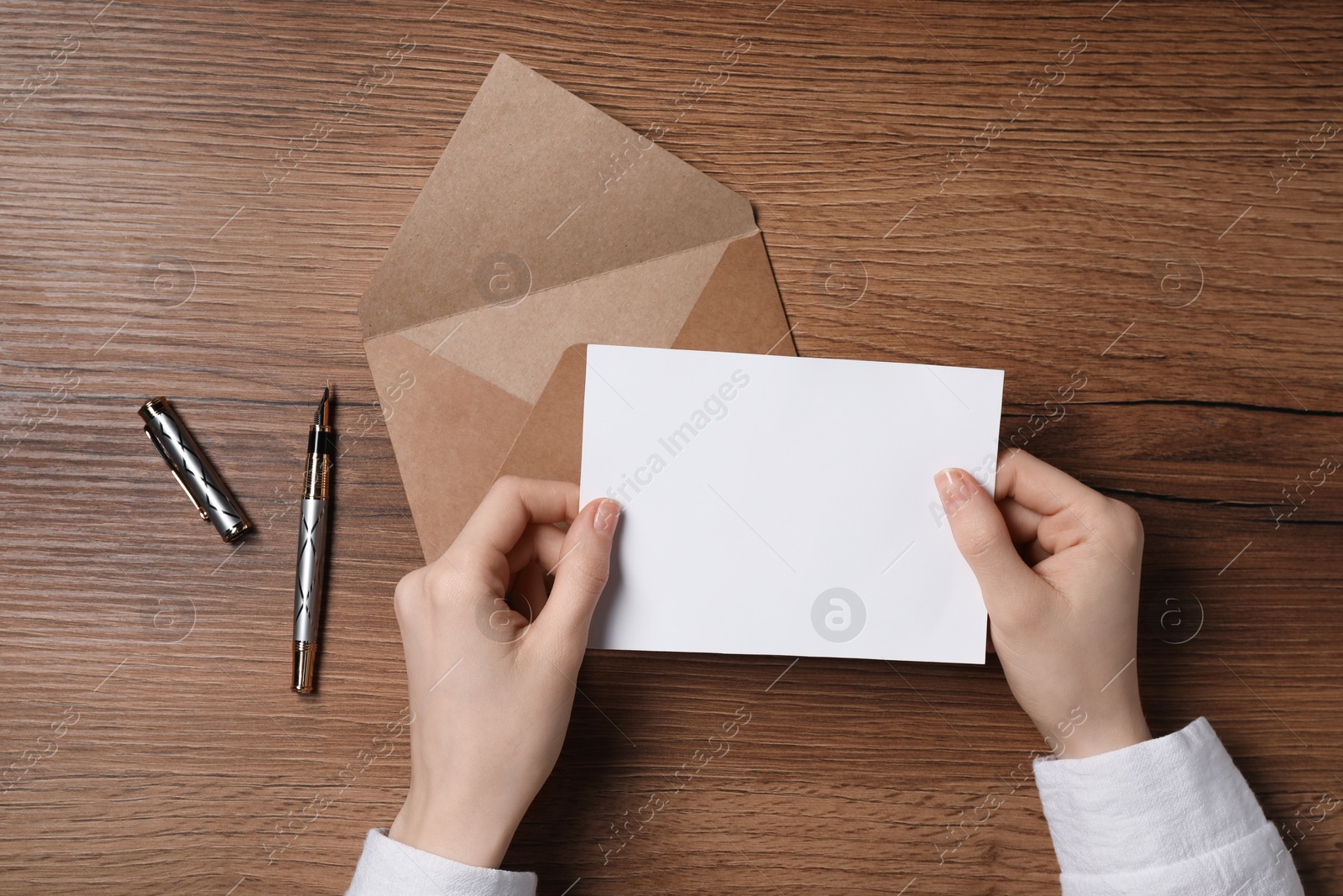 Photo of Woman with blank card at wooden table, top view. Space for text