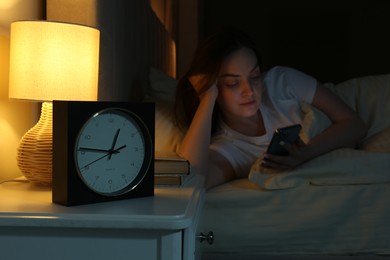 Photo of Woman using smartphone on bed at night, selective focus. Internet addiction