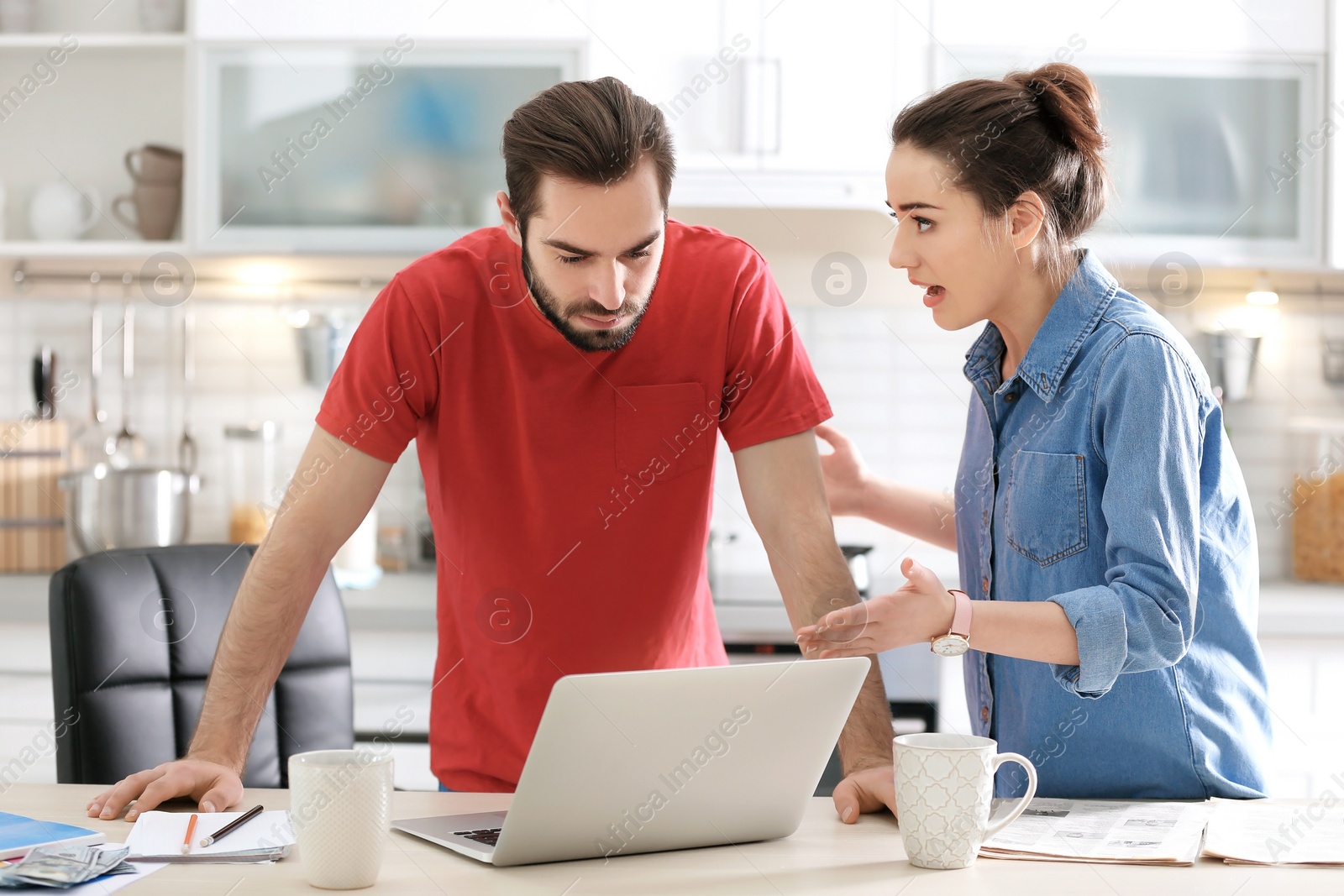 Photo of Young couple having argument about family budget in kitchen