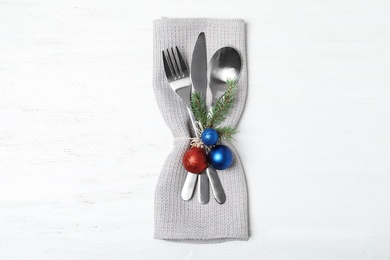 Photo of Cutlery, napkin and Christmas decor on wooden background, top view. Festive table setting