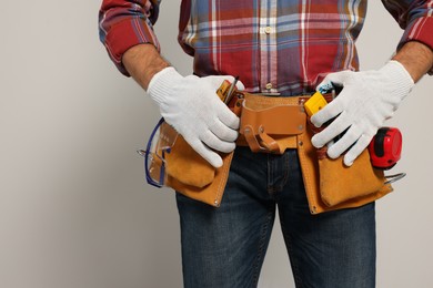 Photo of Professional builder with tool belt on light background, closeup