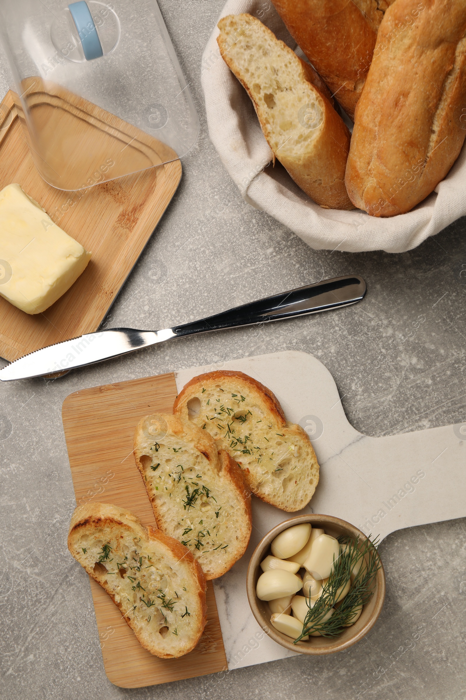 Photo of Tasty baguette with garlic and dill served on light grey table, flat lay