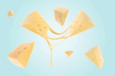 Pieces of cheese falling on light blue background