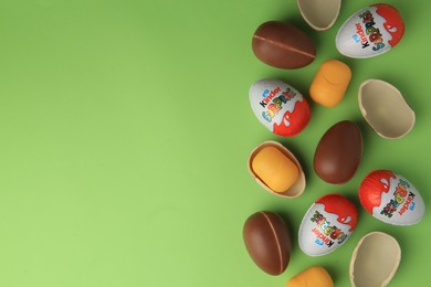 Sveti Vlas, Bulgaria - June 29, 2023: Kinder Surprise Eggs and plastic capsules on light green background, flat lay. Space for text