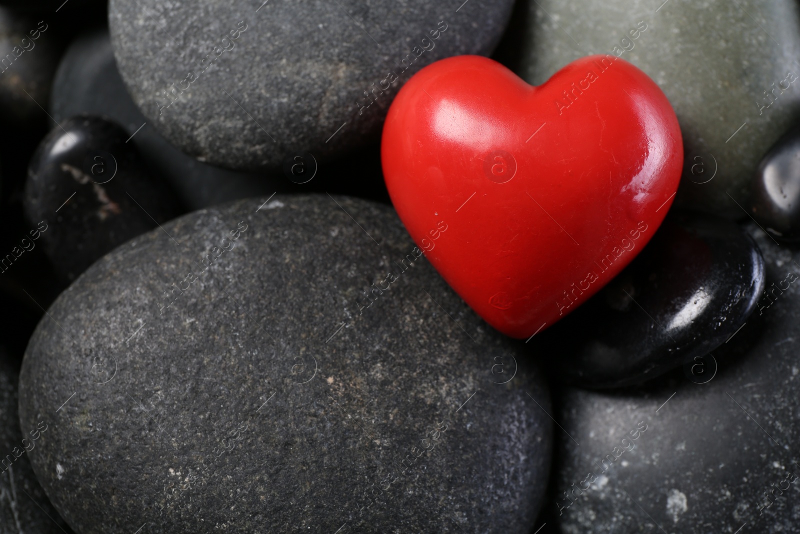 Photo of Red decorative heart on pebble stones, above view