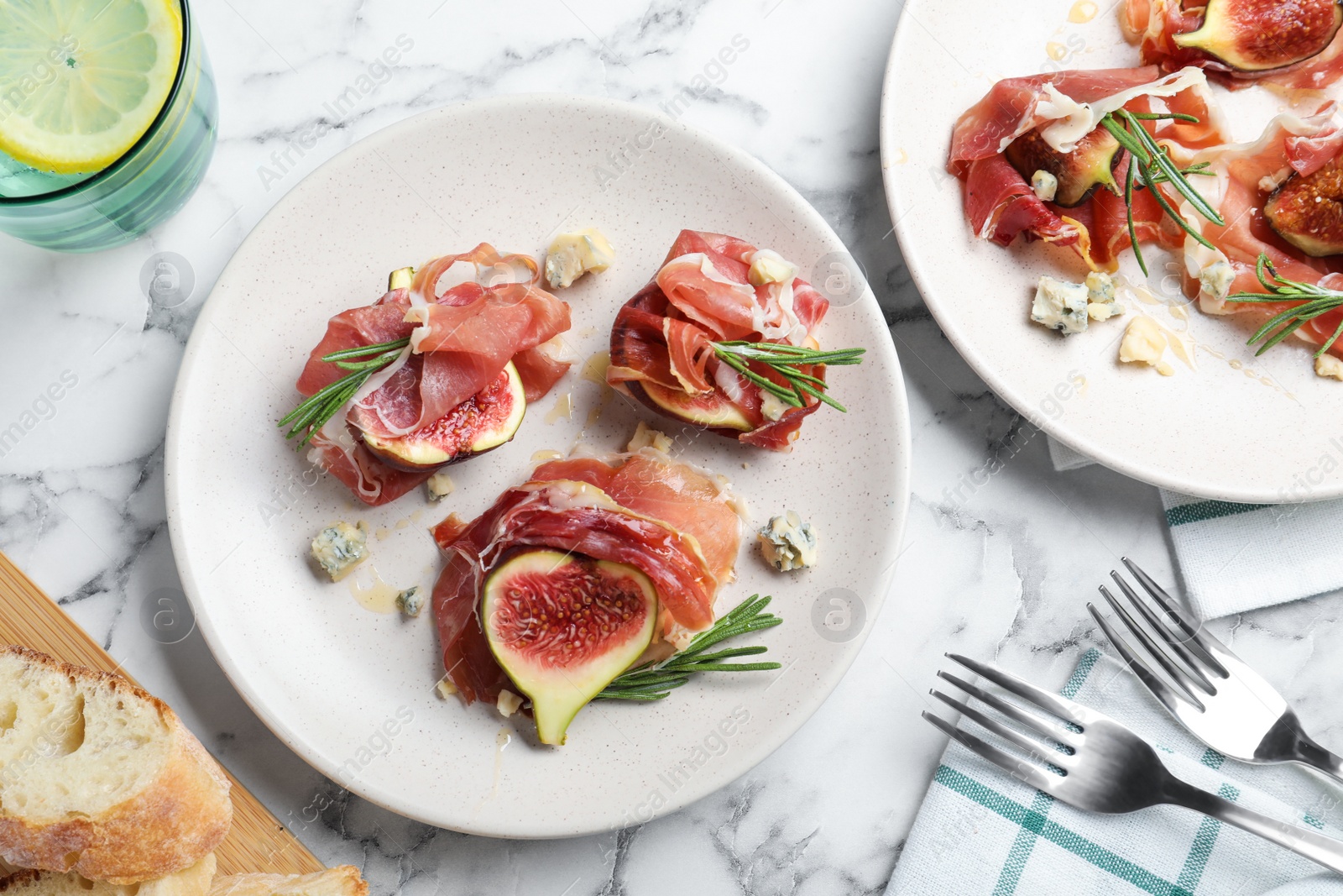 Photo of Delicious ripe figs and prosciutto served on white marble table, flat lay