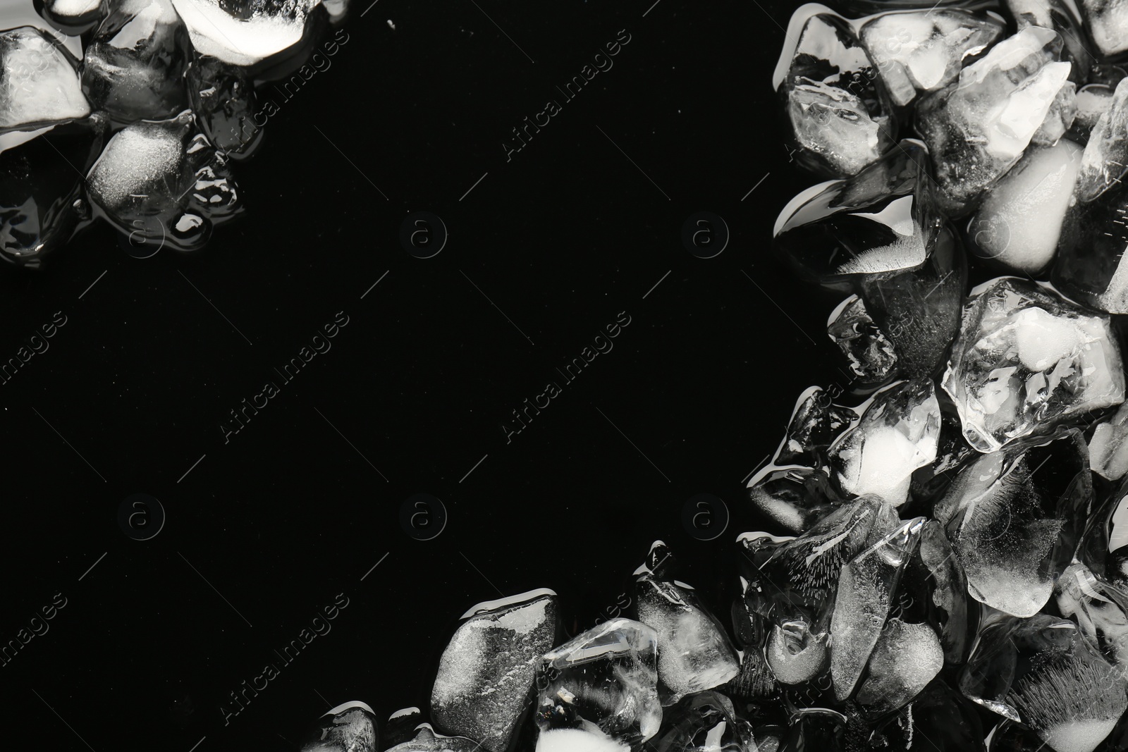 Photo of Pieces of crushed ice on black background, top view. Space for text
