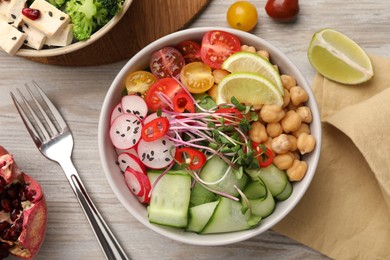 Photo of Bowl with many different vegetables on white wooden table, flat lay. Vegan diet
