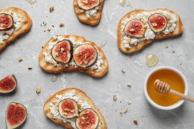 Photo of Bruschettas with cheese, figs and honey on marble table, flat lay