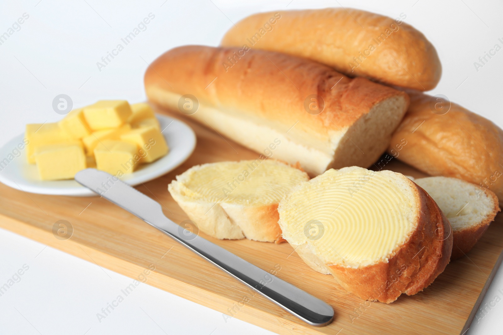 Photo of Whole and cut baguettes with fresh butter on white background, closeup