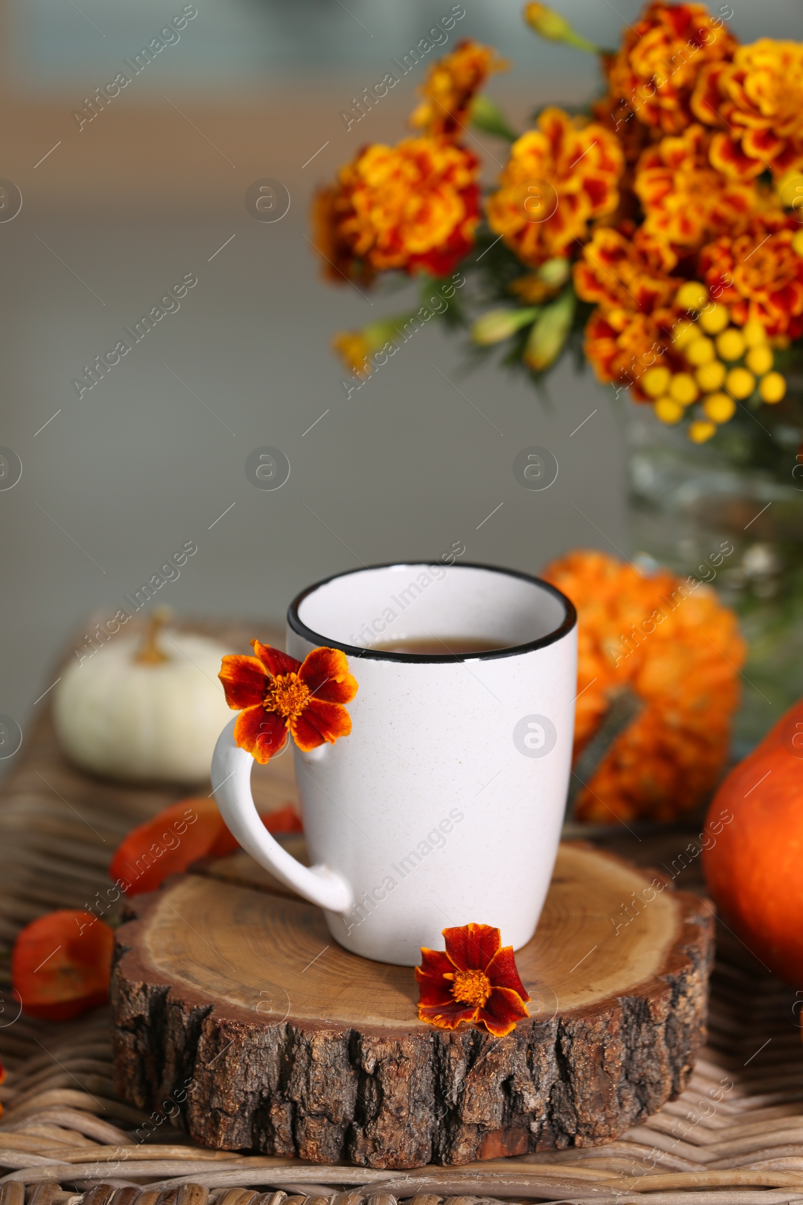 Photo of Beautiful autumn composition with cup of drink and flowers on wicker table