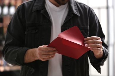 Man holding envelope with greeting card indoors, closeup