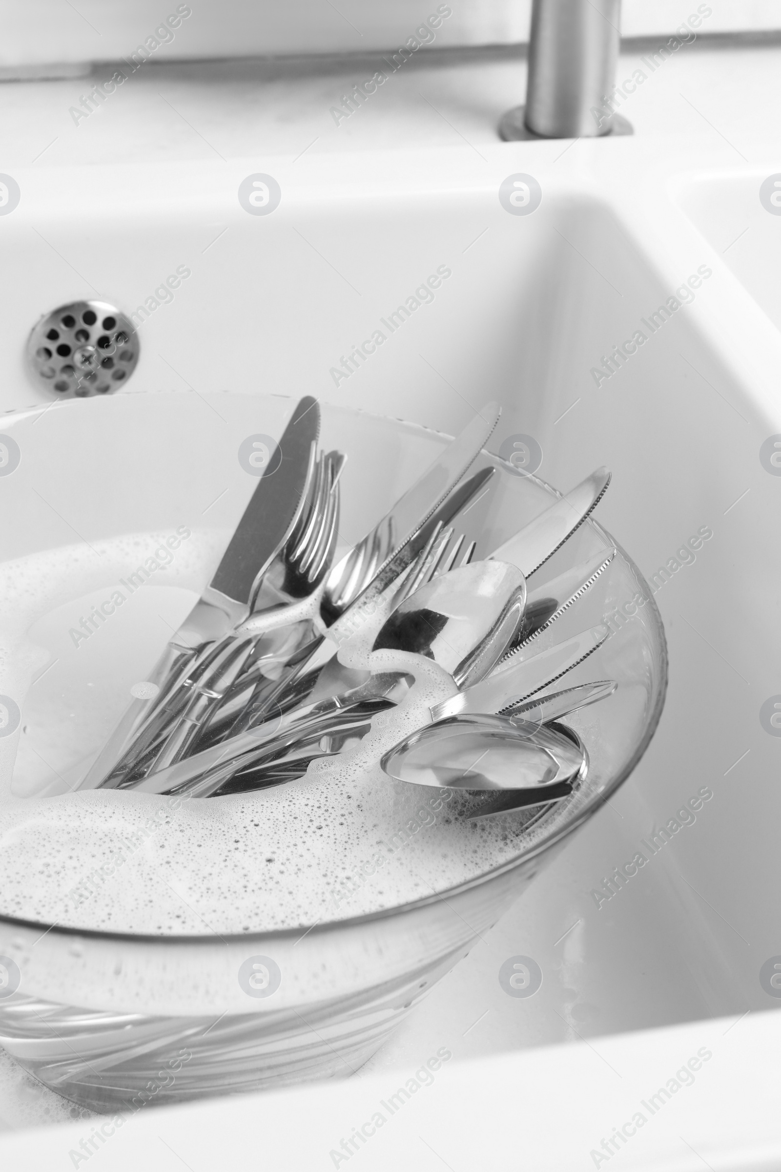 Photo of Washing silver spoons, forks and knives in kitchen sink