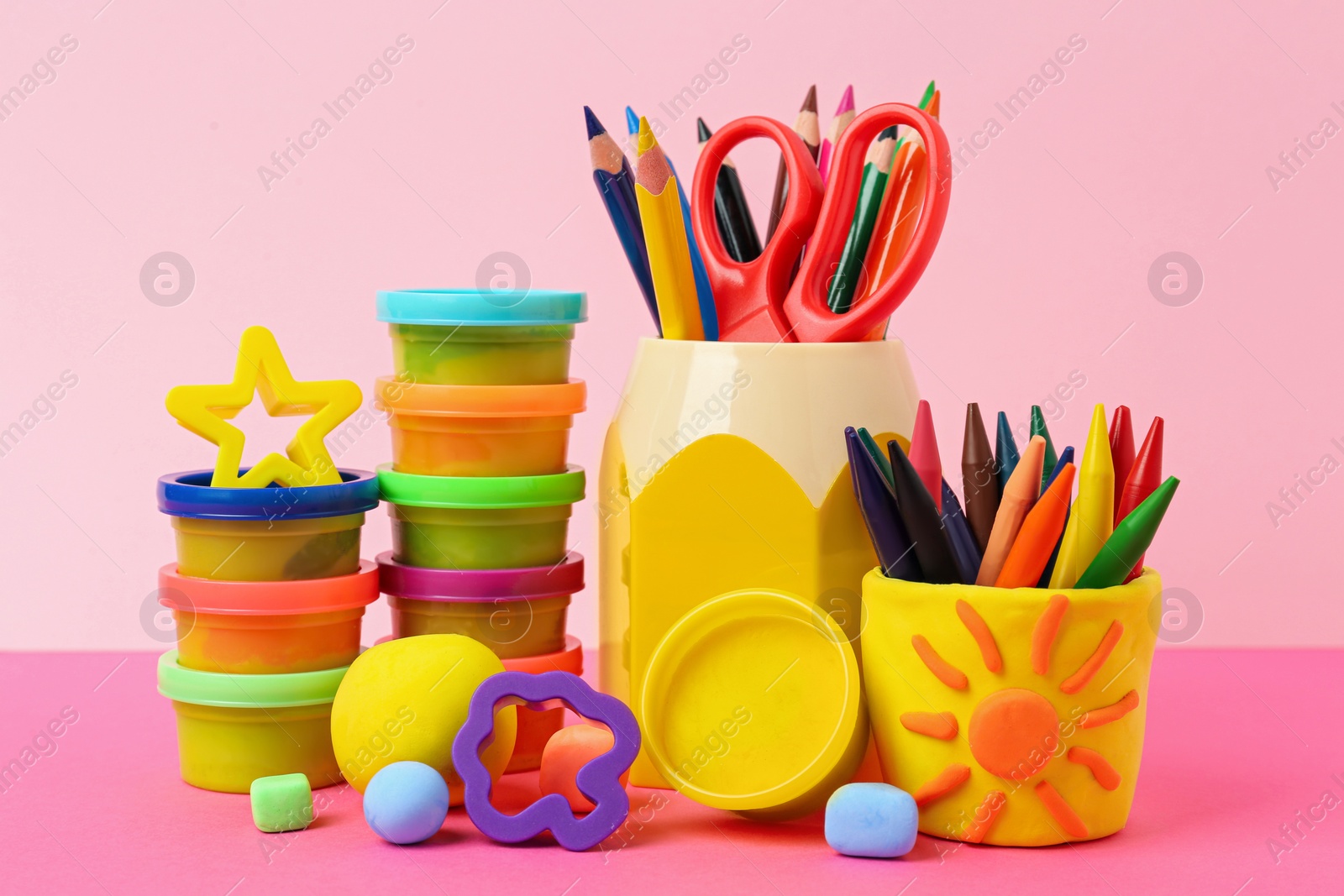 Photo of Set of bright play dough with tools and pencils on color background