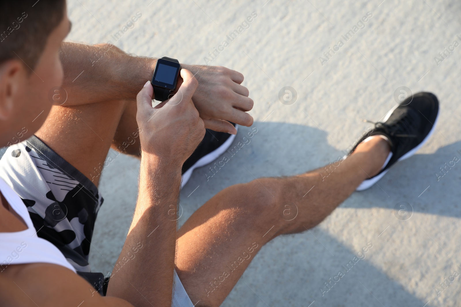 Photo of Man checking fitness tracker after training outdoors, closeup