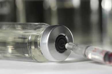 Photo of Filling syringe with medicine from vial on table, closeup