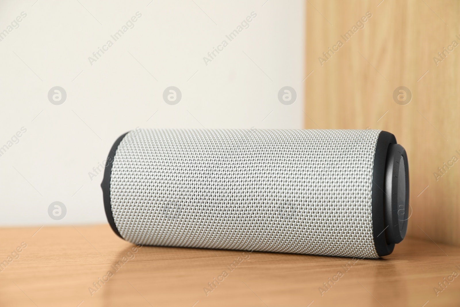 Photo of One portable bluetooth speaker on wooden table. Audio equipment