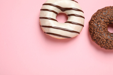 Photo of Delicious glazed donuts on pink background, flat lay. Space for text