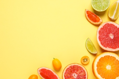 Photo of Fresh juicy citrus fruits on light yellow background, flat lay. Space for text